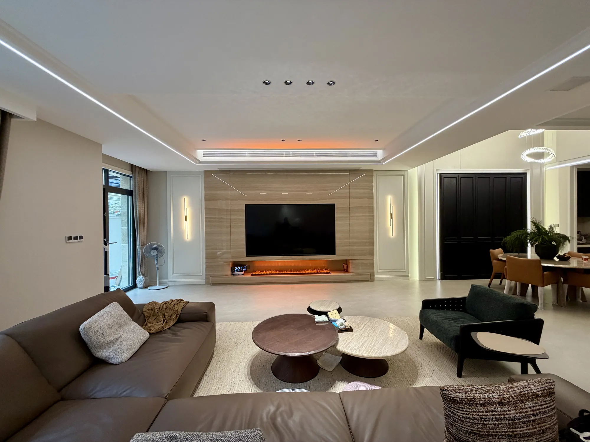 Wide living room view with warm timber media wall and layered ceiling light
