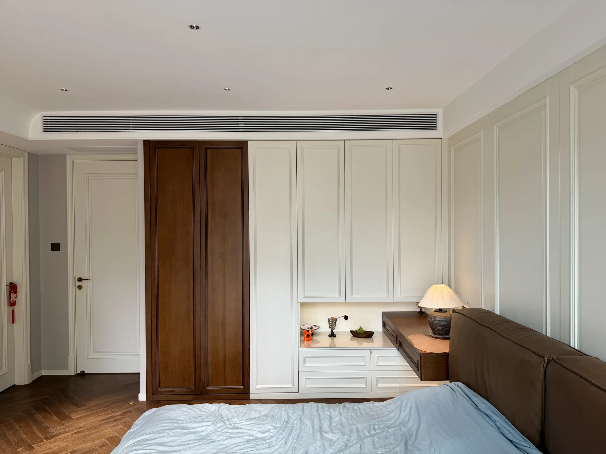 Wide bedroom view with integrated headboard, desk and storage wall