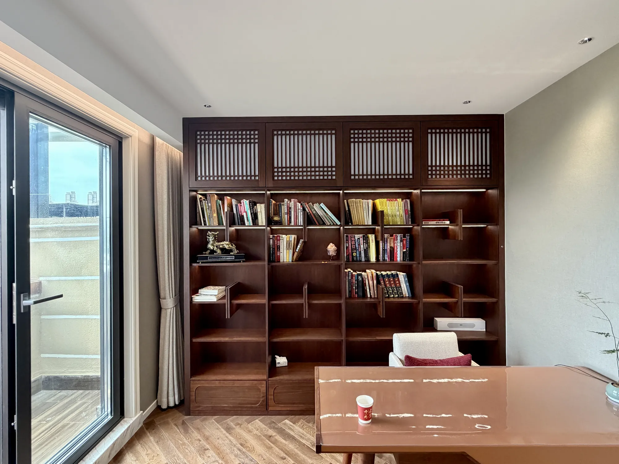 Warm timber home library with full-height shelving and integrated desk