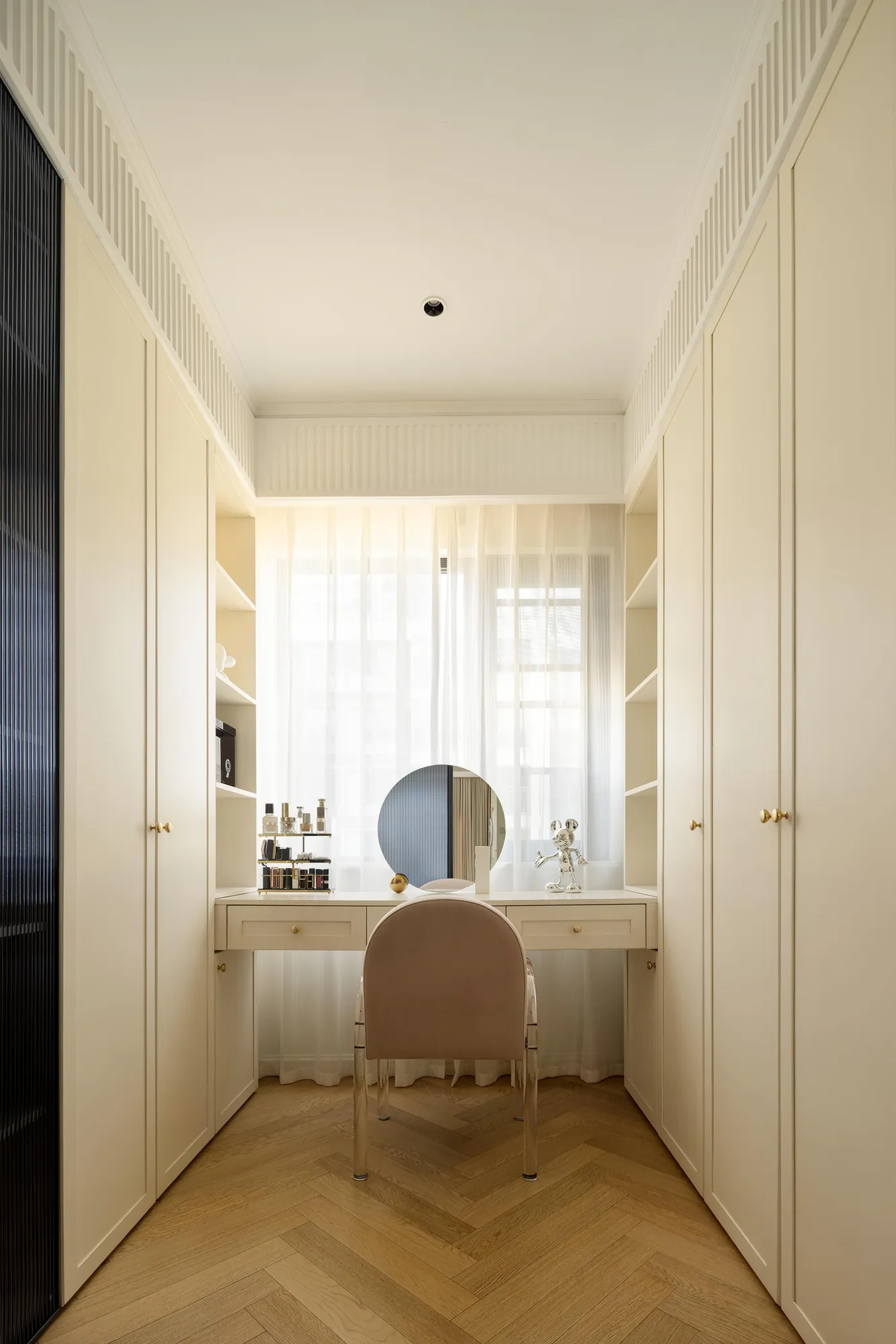 Dressing corridor with integrated wardrobes and a window-facing vanity