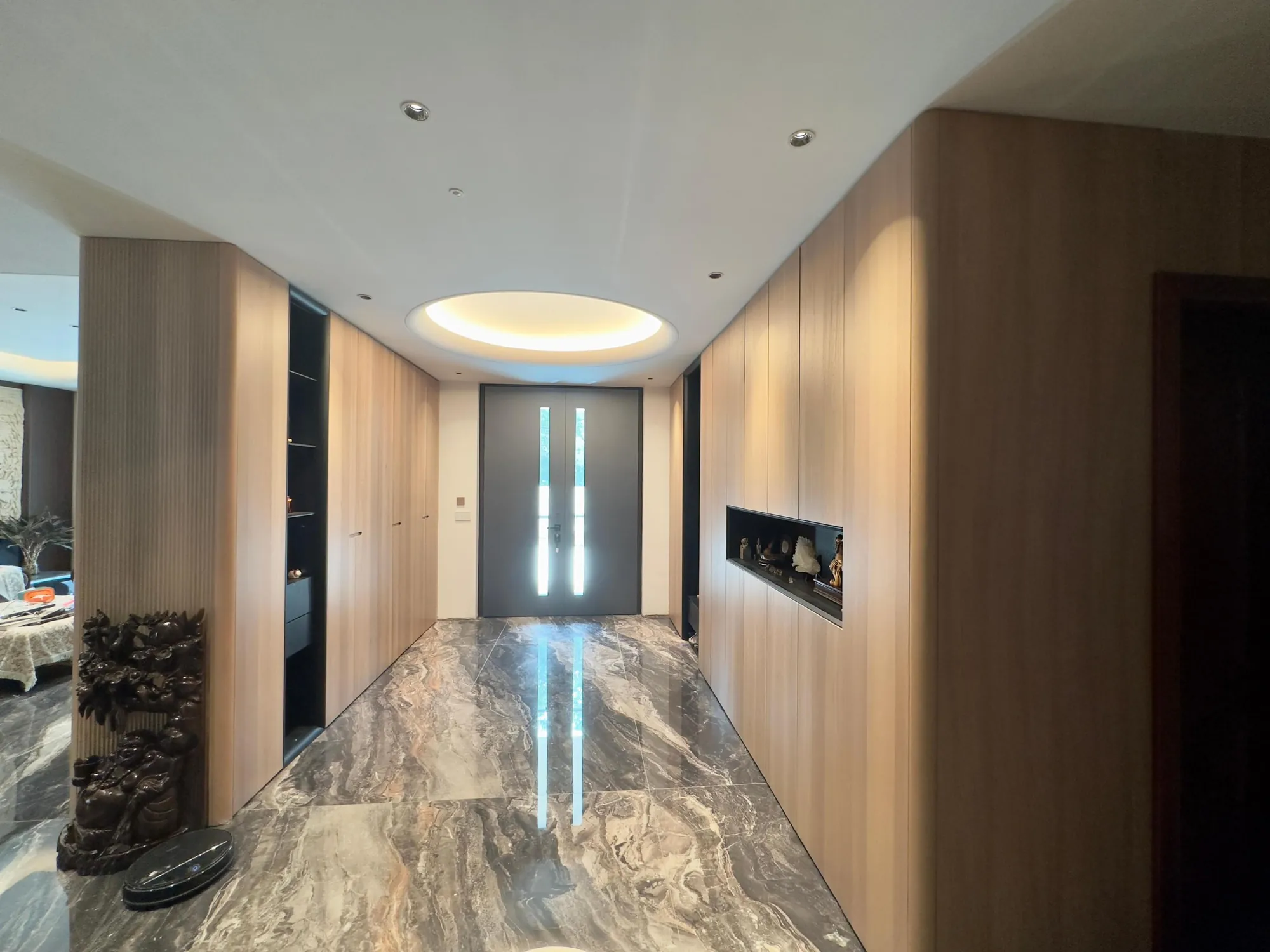 Entrance hall with full-height fitted storage, dark display niches and pale stone floor