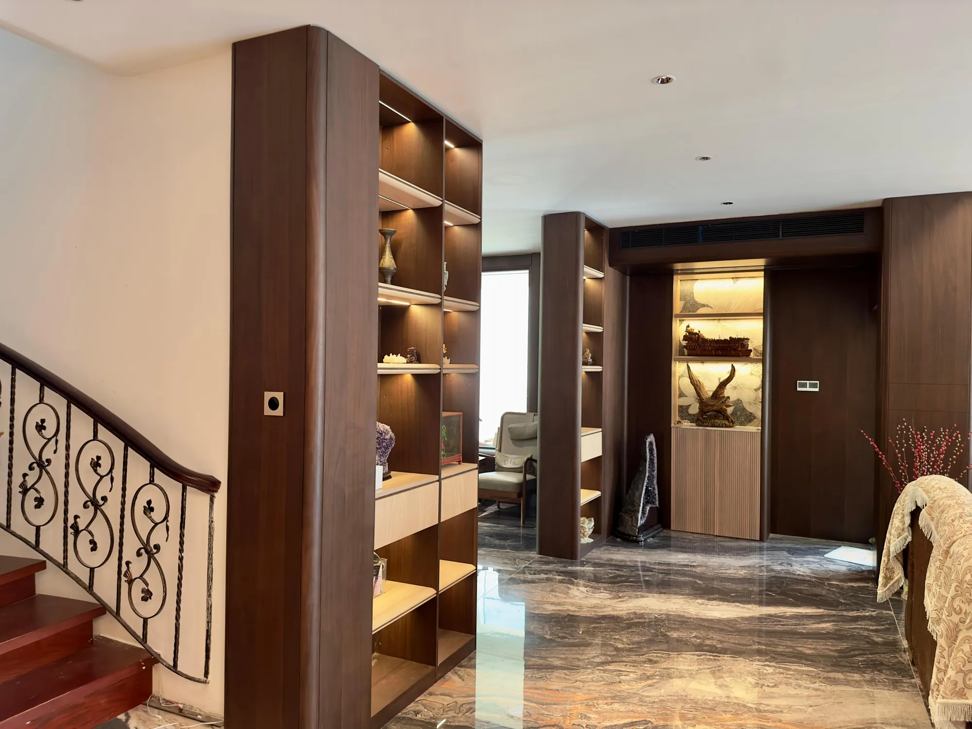 Stair hall with dark full-height joinery and illuminated display recesses