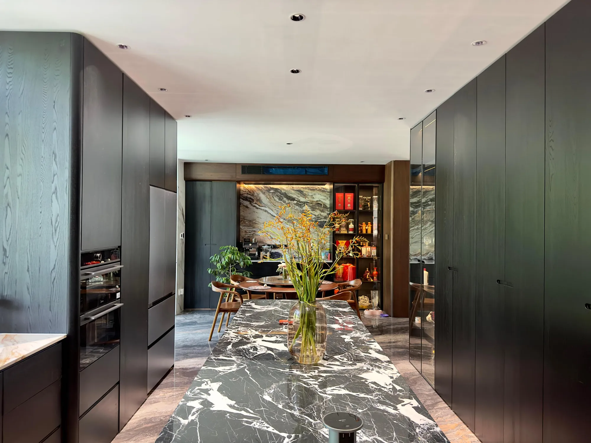 Dark timber villa kitchen with expressive marble floor, island and full-height cabinetry