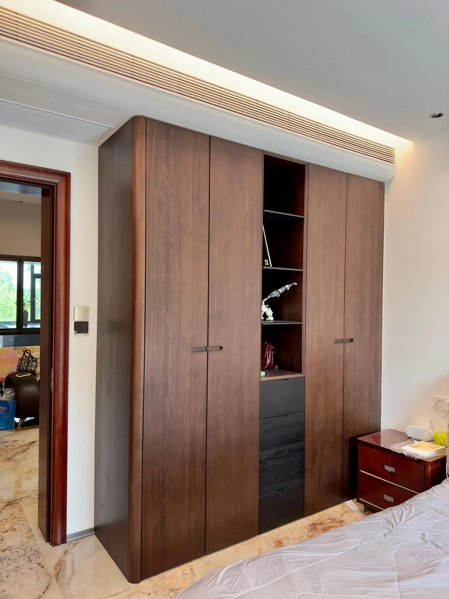 Bedroom with dark walnut wardrobes, integrated lighting and fitted dressing storage