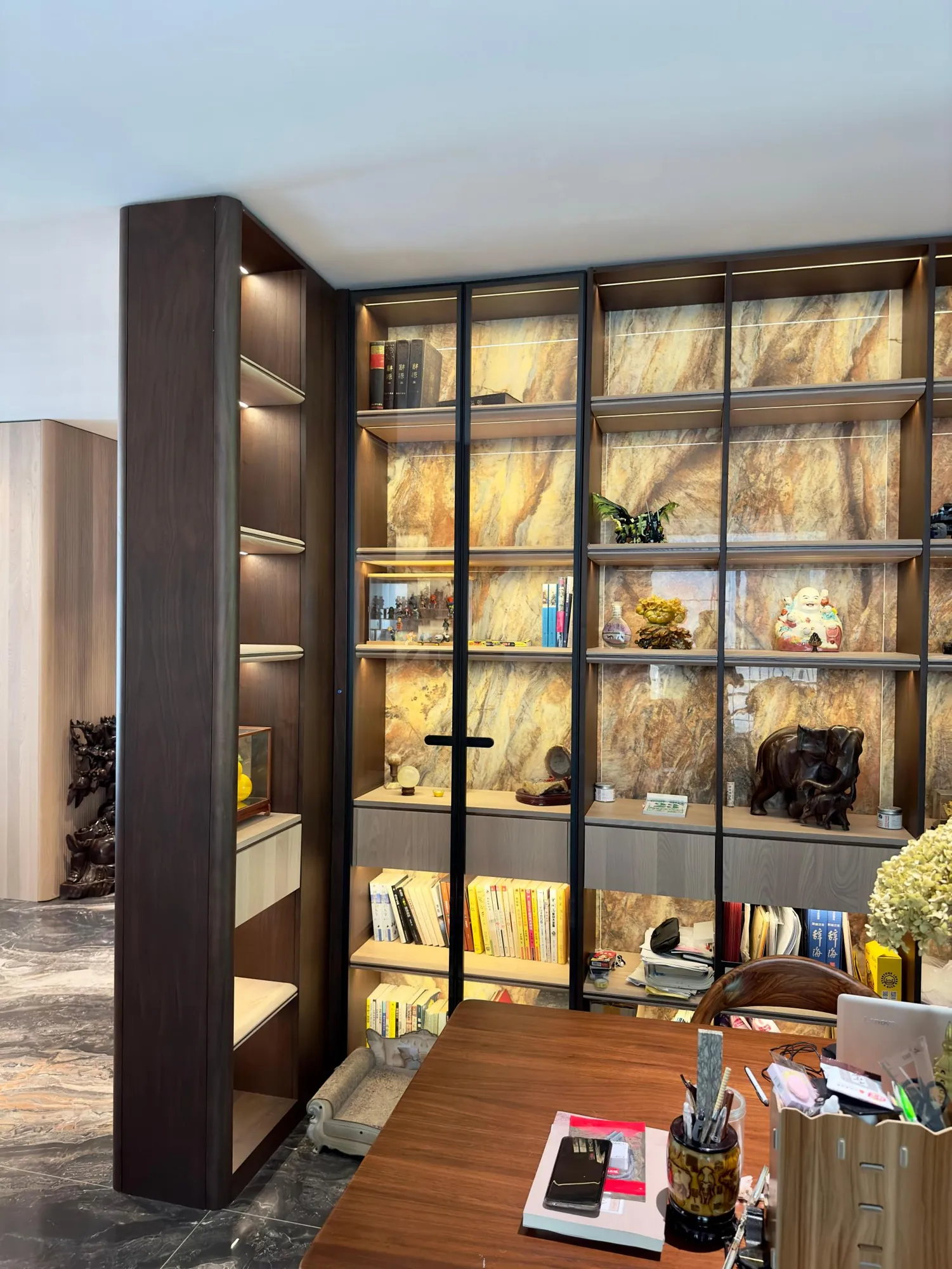 Study with glass-front display cabinetry, dark framing and integrated warm lighting