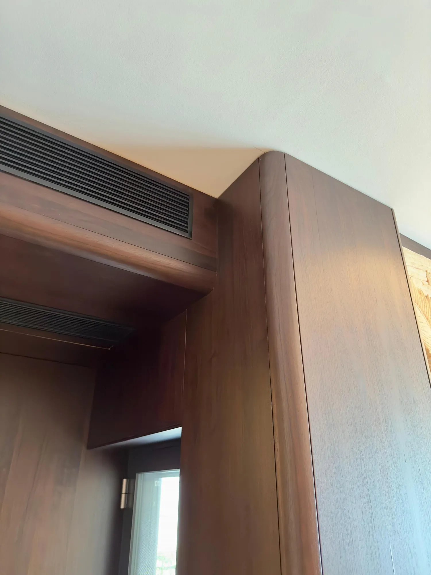 Rounded cabinet end and integrated air-conditioning detail within the kitchen joinery