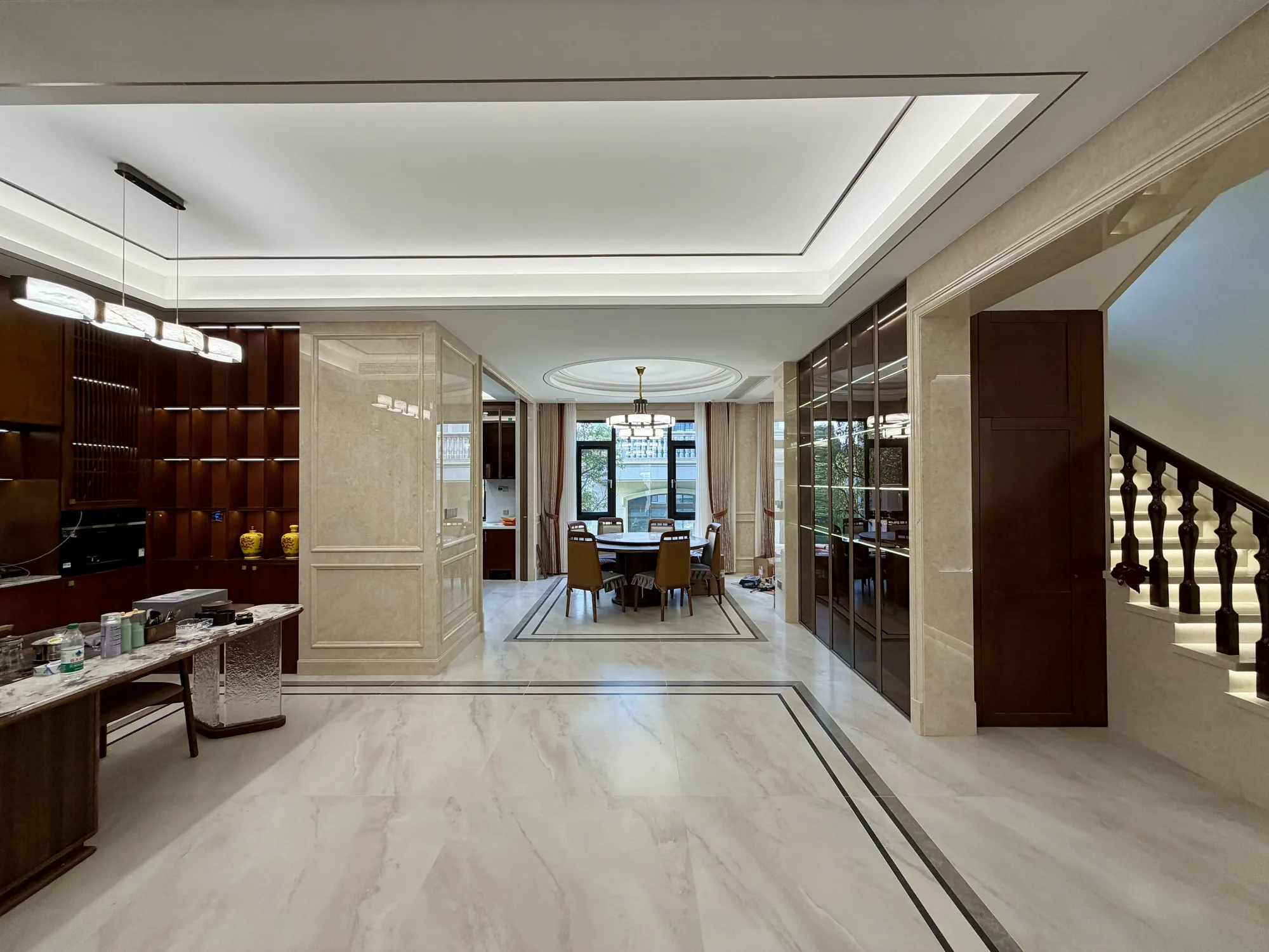 Open living and dining sequence with walnut joinery and framed stone floor
