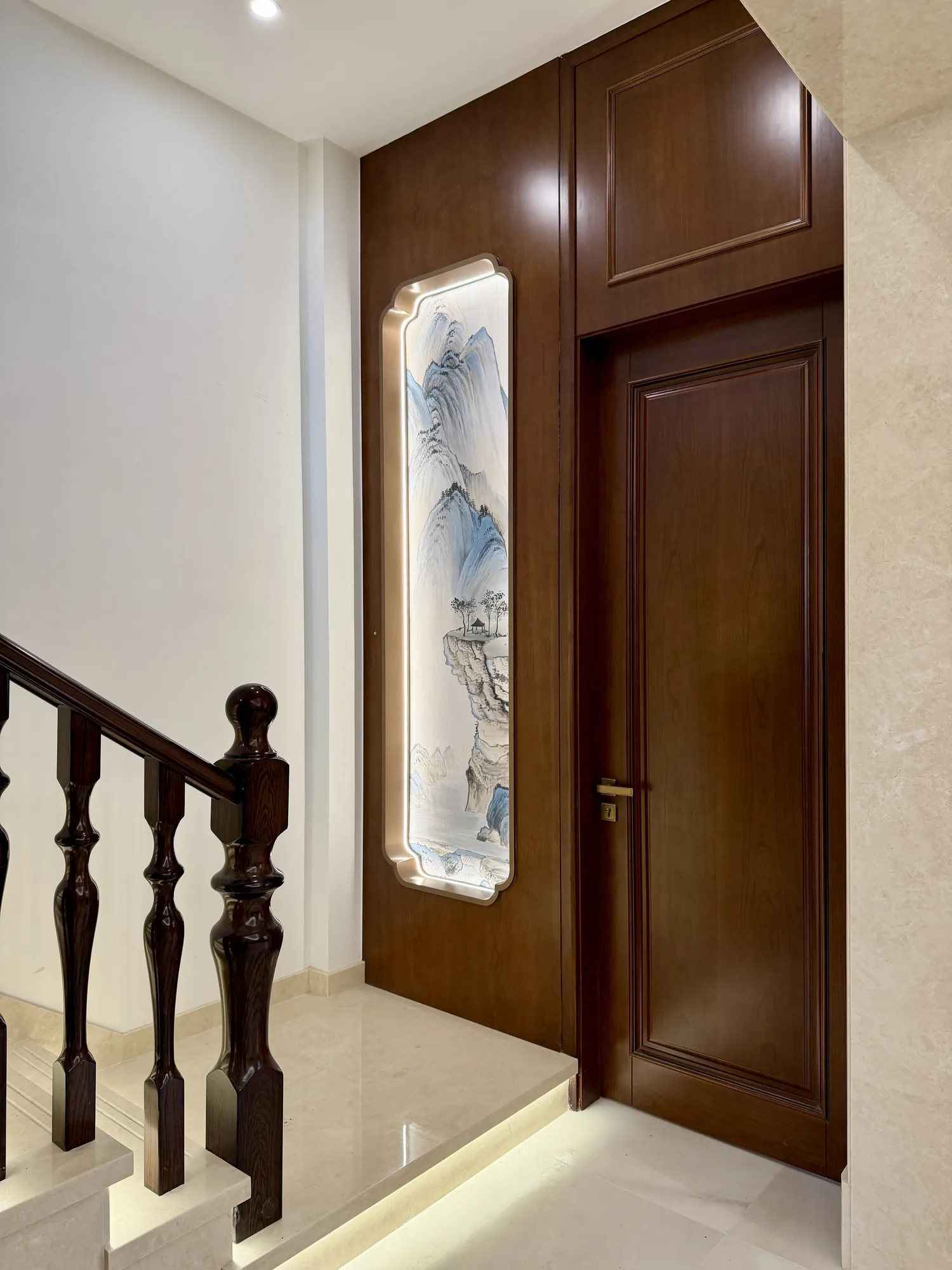 Illuminated stair with walnut balustrade and tall decorative wall light