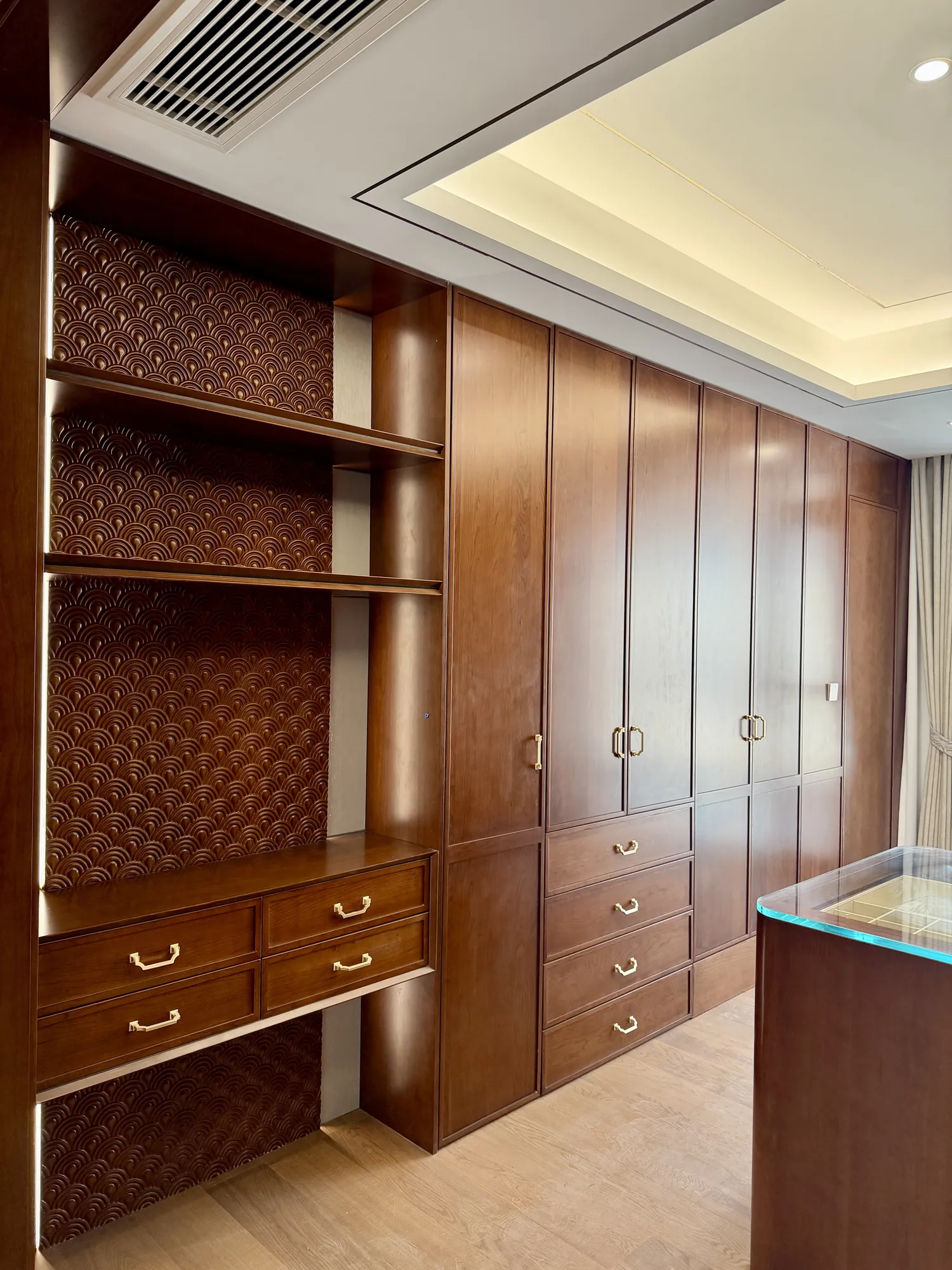 Bedroom with walnut wall panels, fitted media unit and layered ceiling light