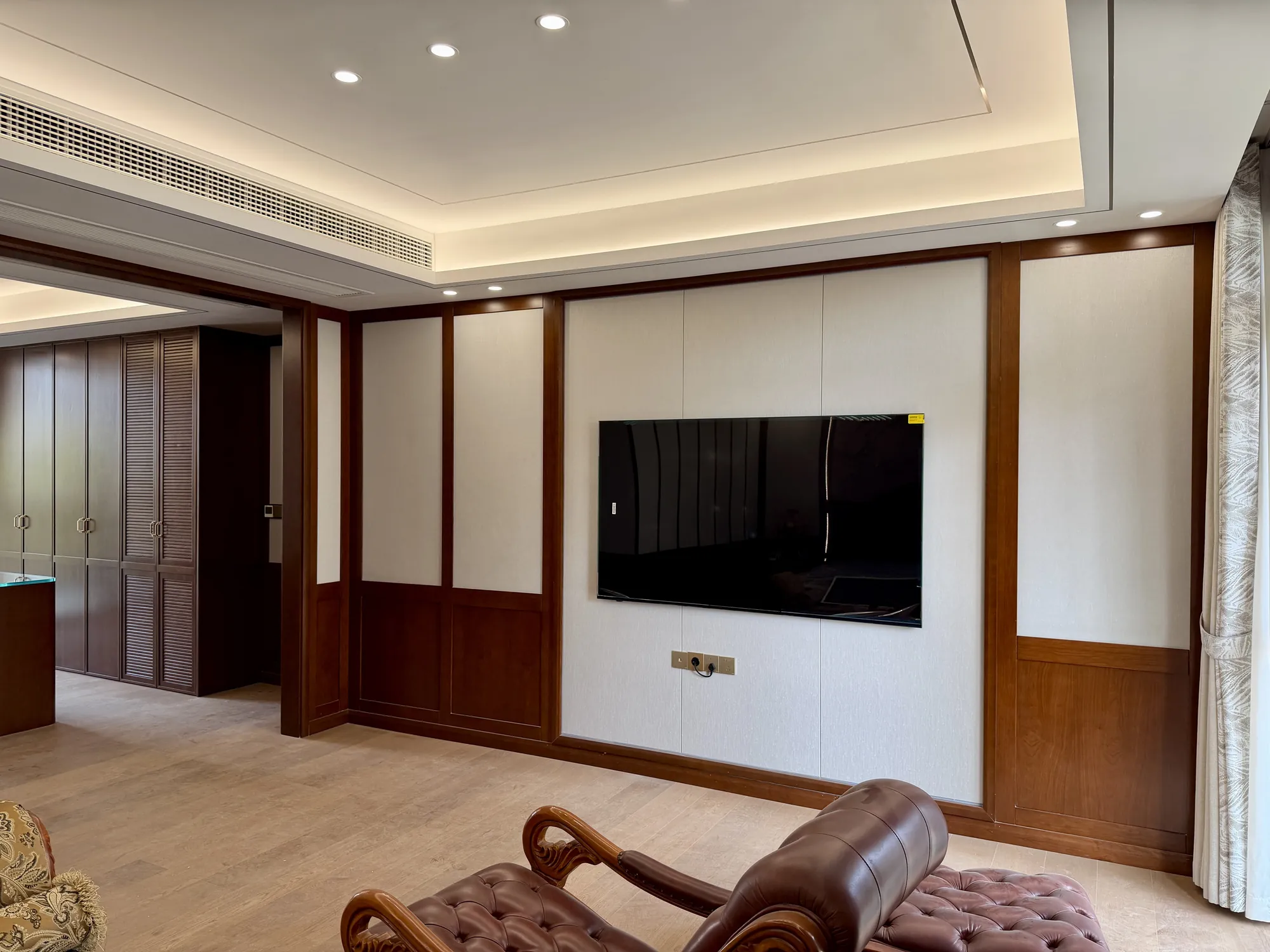 Walnut panelled bedroom with upholstered bed and fitted storage