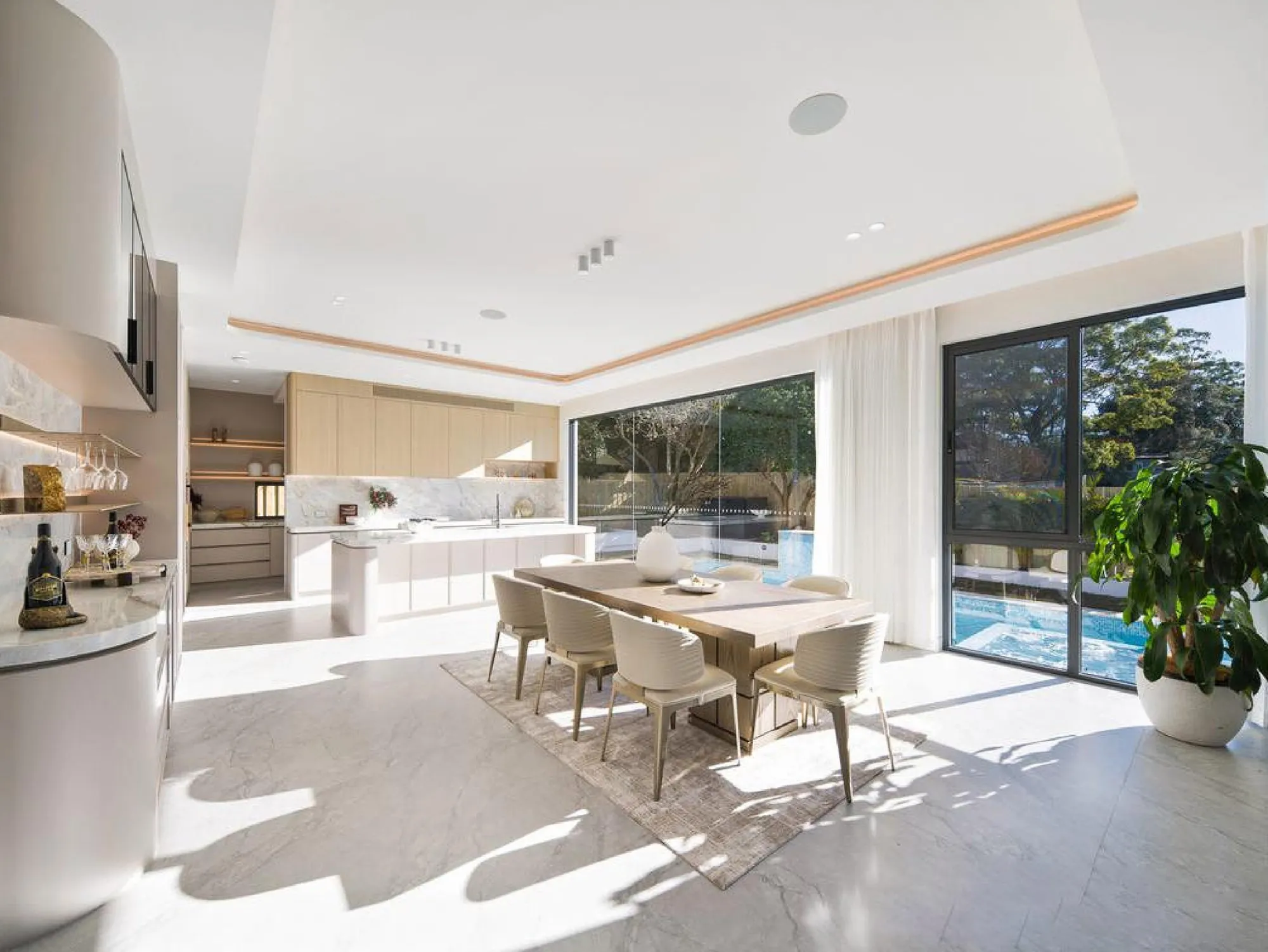 Daylit kitchen and dining room with pale cabinetry, stone surfaces and garden glazing