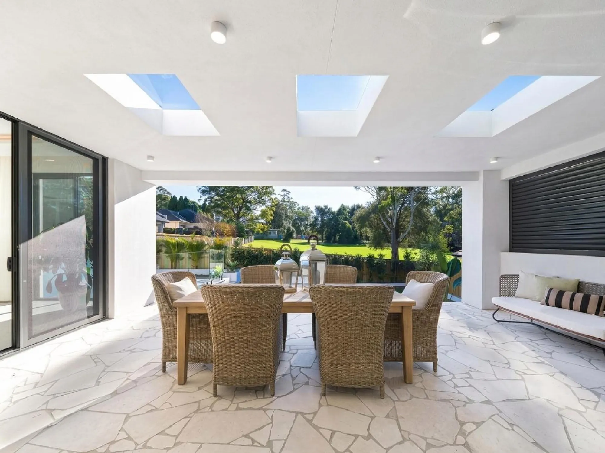 Covered alfresco dining terrace with skylights and pale irregular stone floor