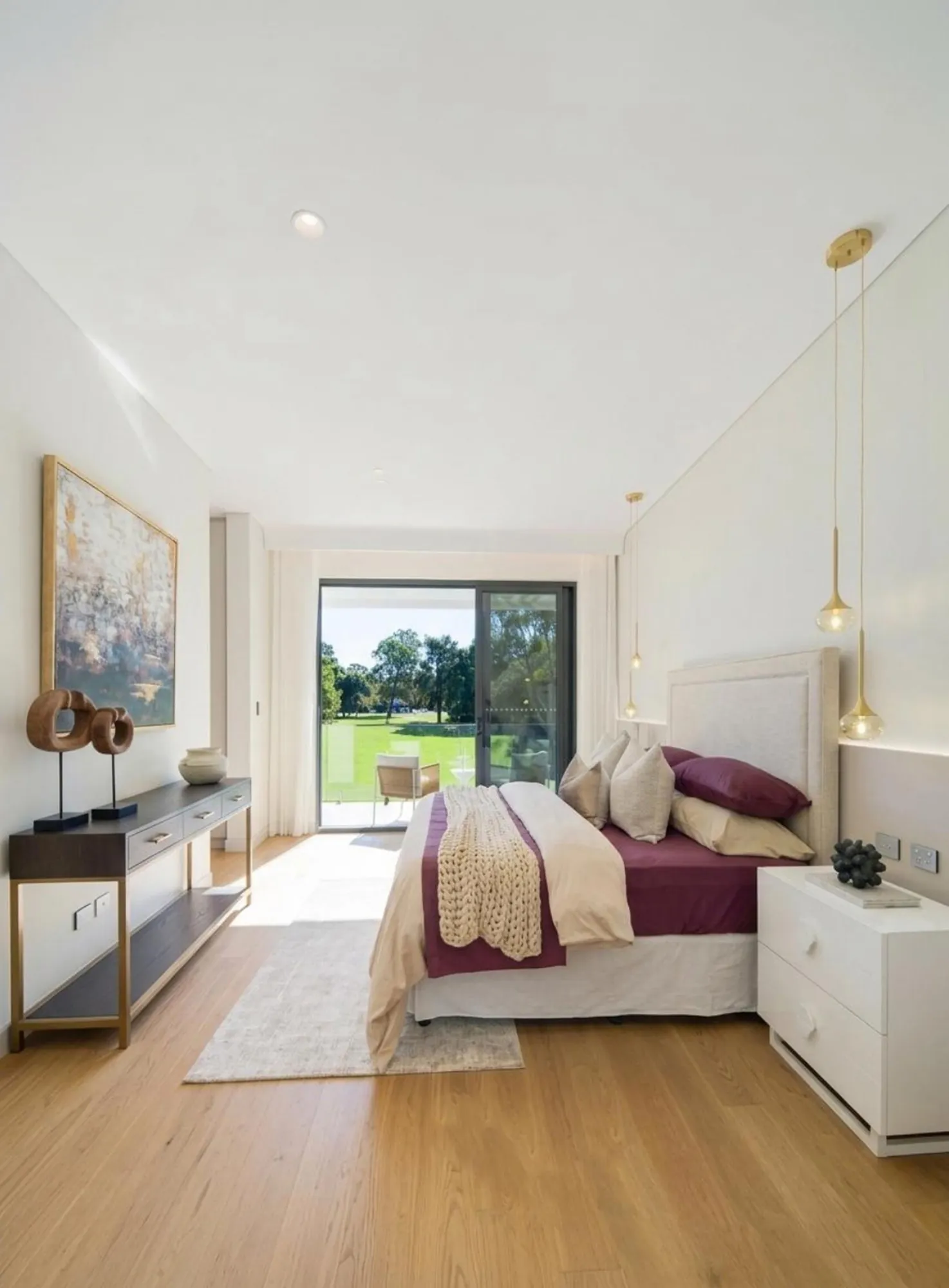 Main bedroom with pale wall panels, low storage and balcony outlook