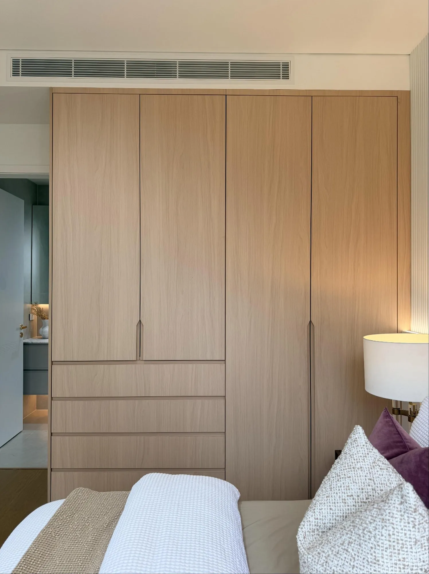 Pale fitted bedroom wardrobe aligned below the ceiling grille