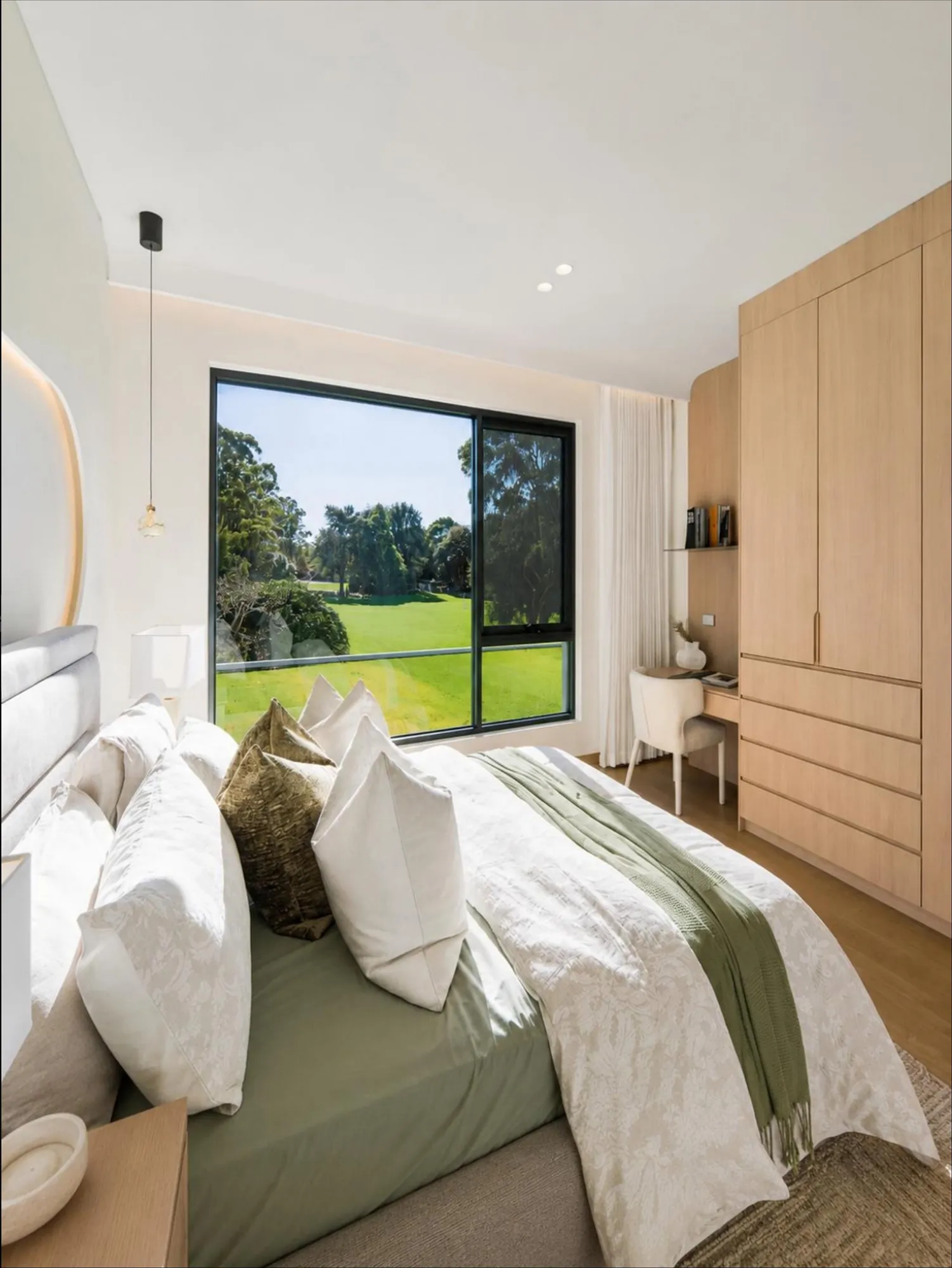 Secondary bedroom with full-height pale timber wardrobe and integrated desk