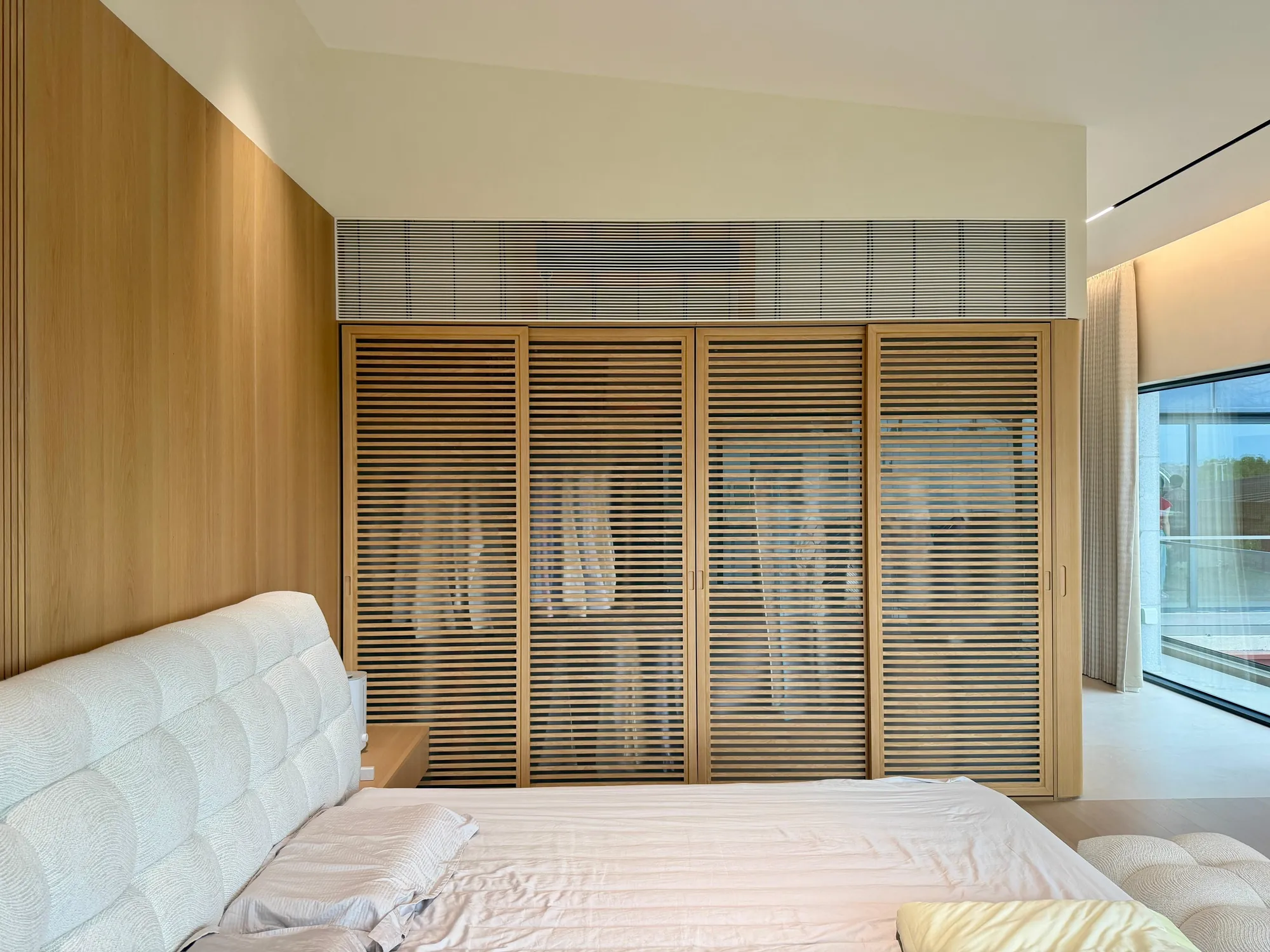 Main bedroom with walnut louvre wardrobes and floor-to-ceiling glazing