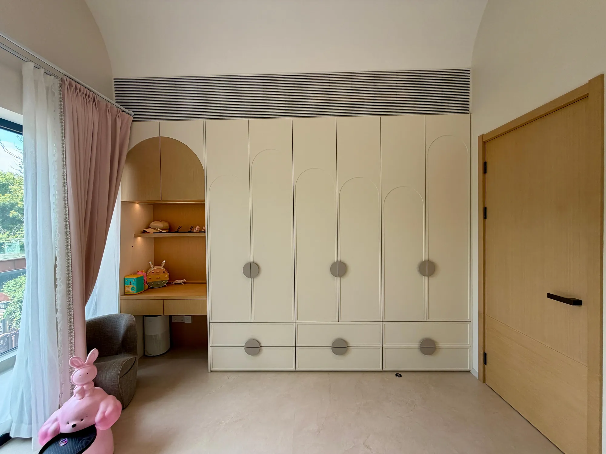 Child bedroom with cream wardrobes and a rounded built-in study niche