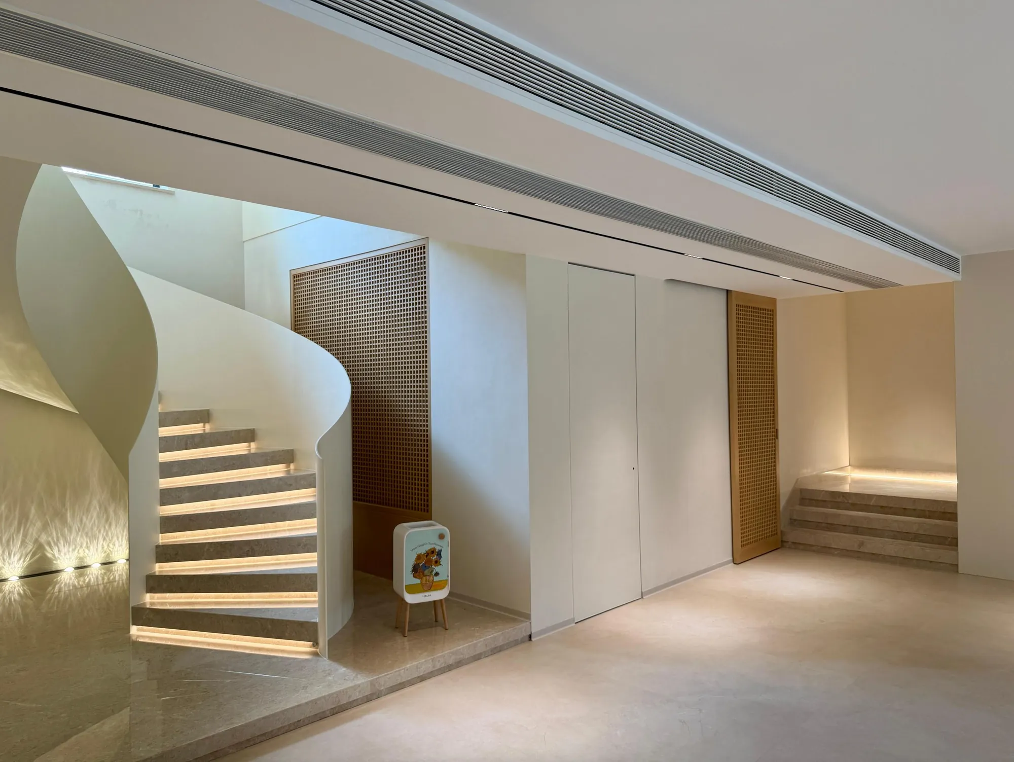 Curved white stair with integrated step lighting and pale stone floor