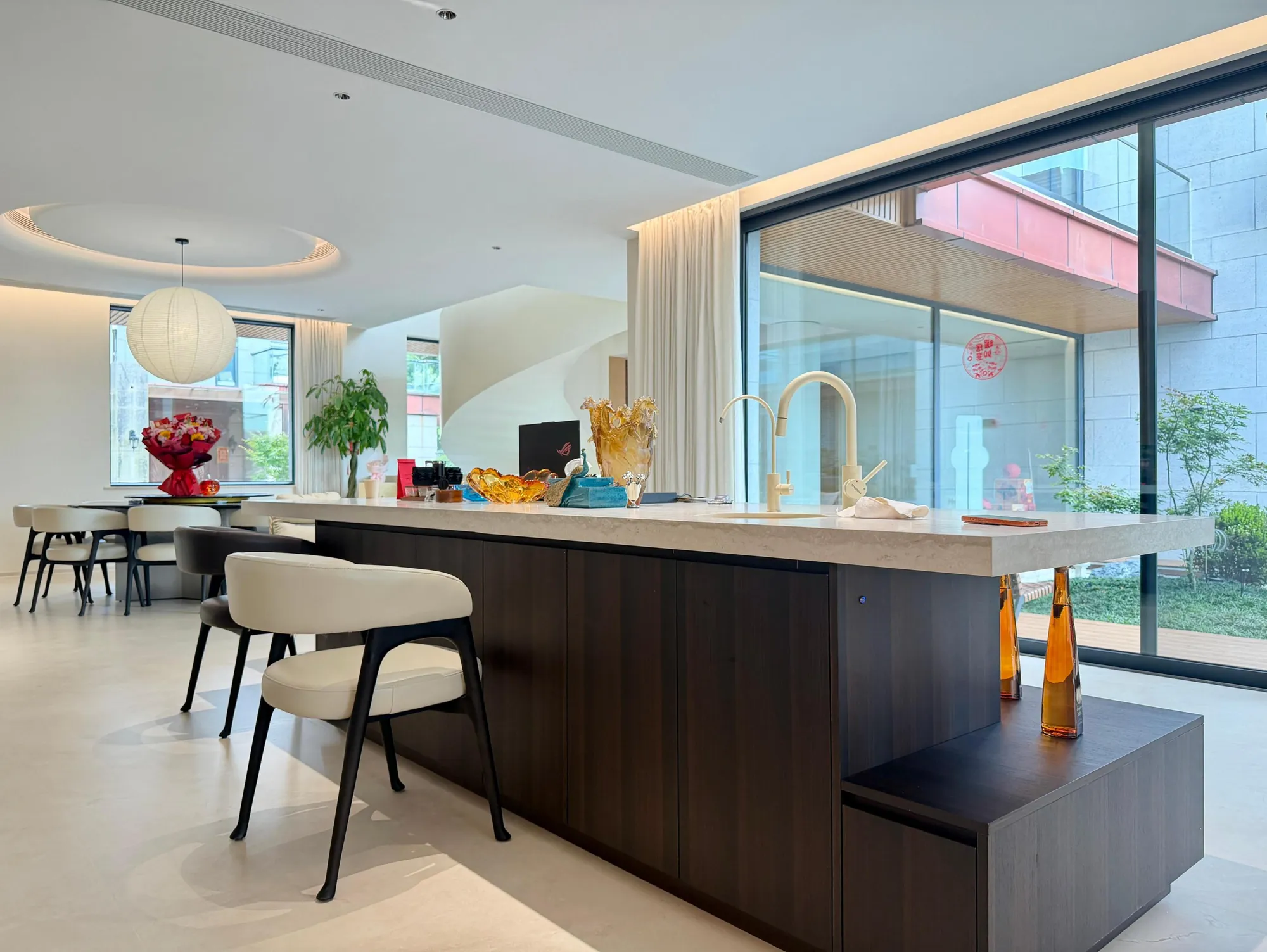 Dark timber kitchen island beside full-height garden glazing