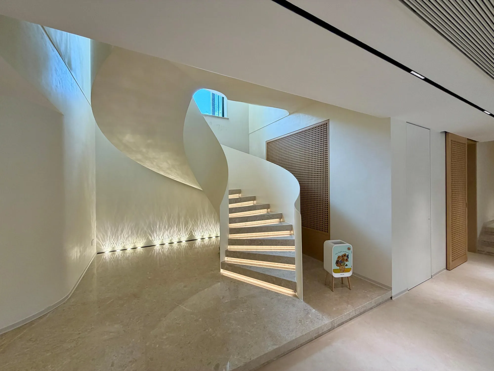 Curved stair with illuminated handrail and smooth pale surfaces