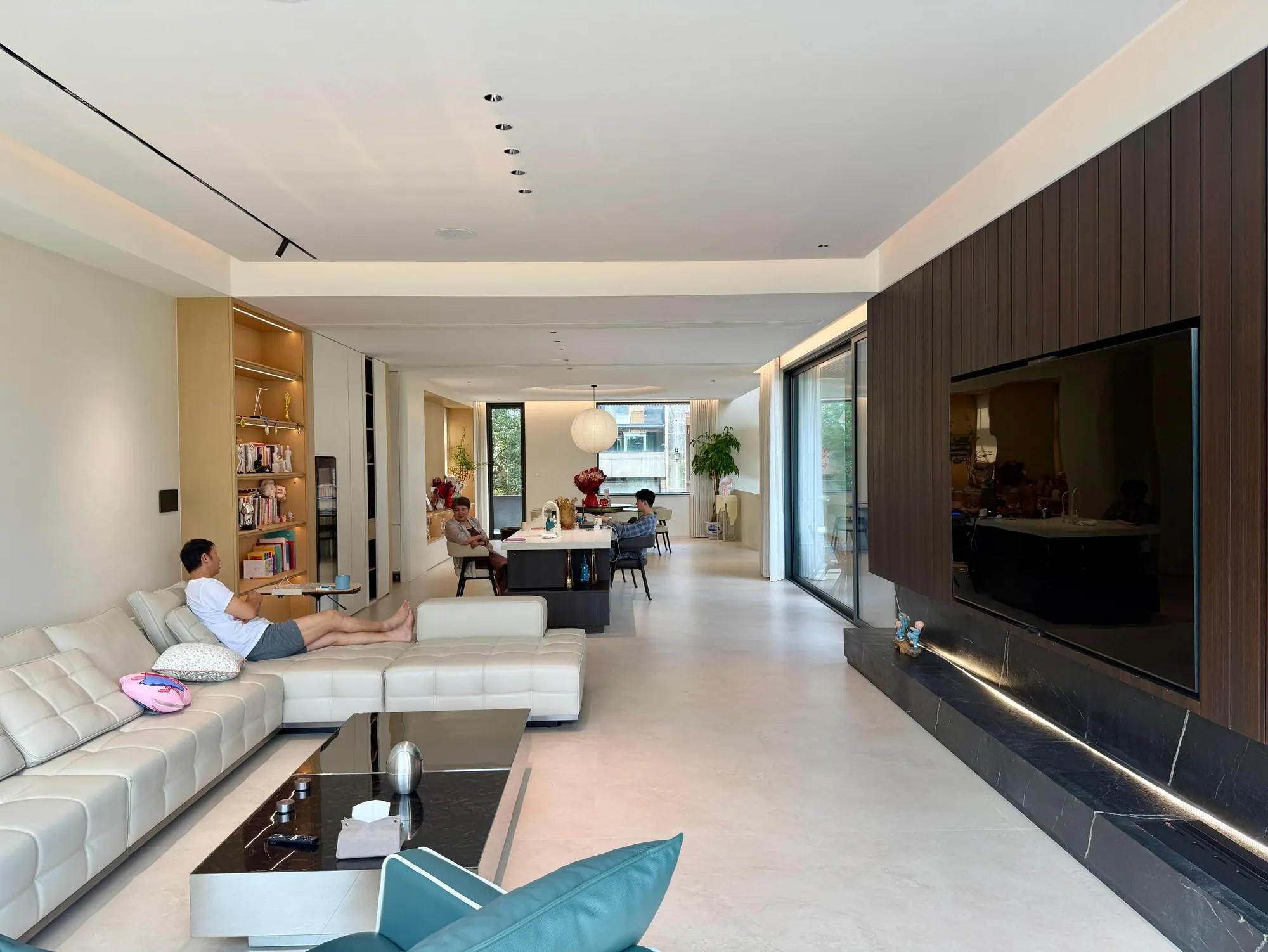 Long living room with pale seating and dark timber media wall