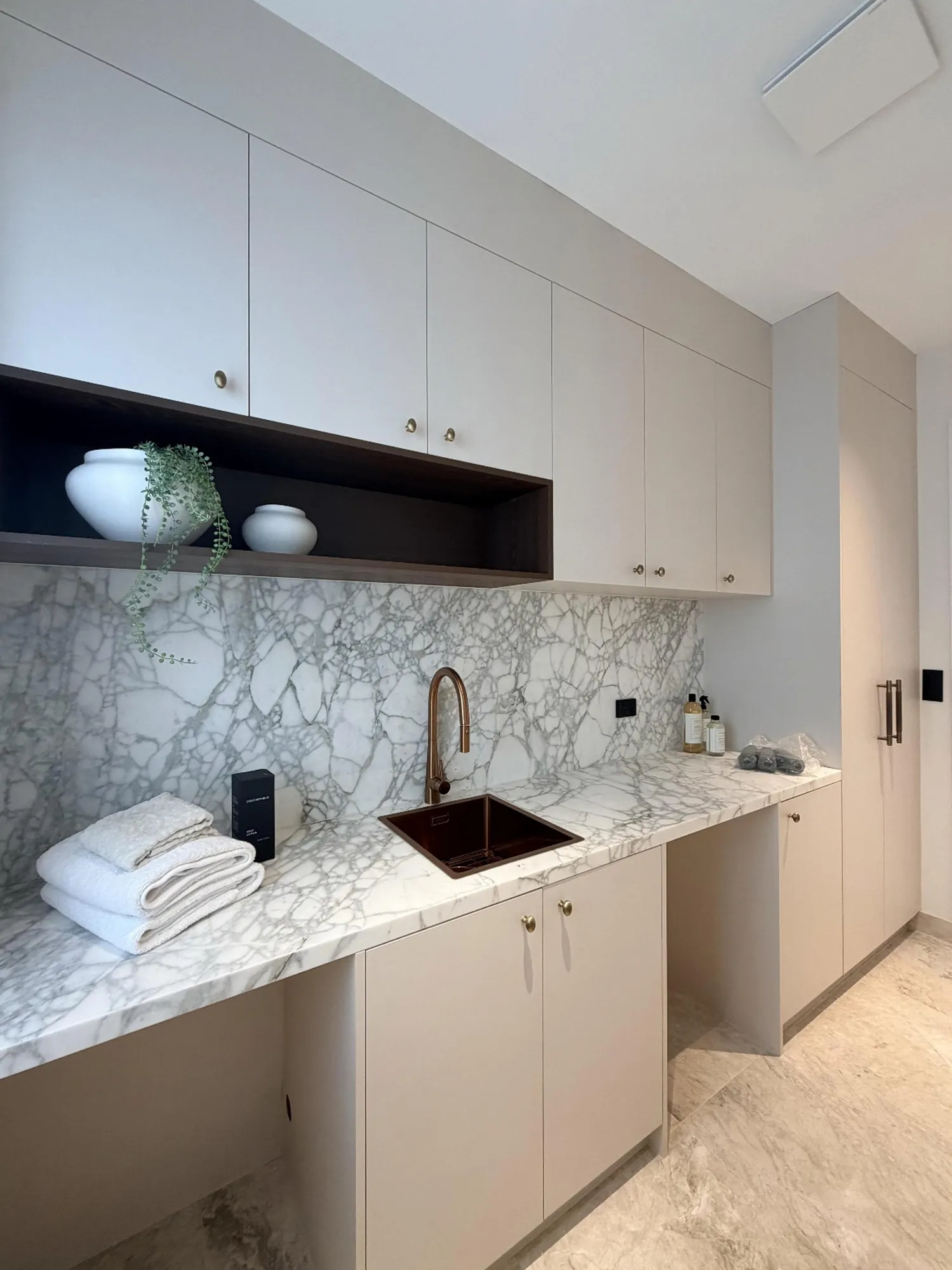 Fitted laundry with pale cabinetry and a dark stone work surface
