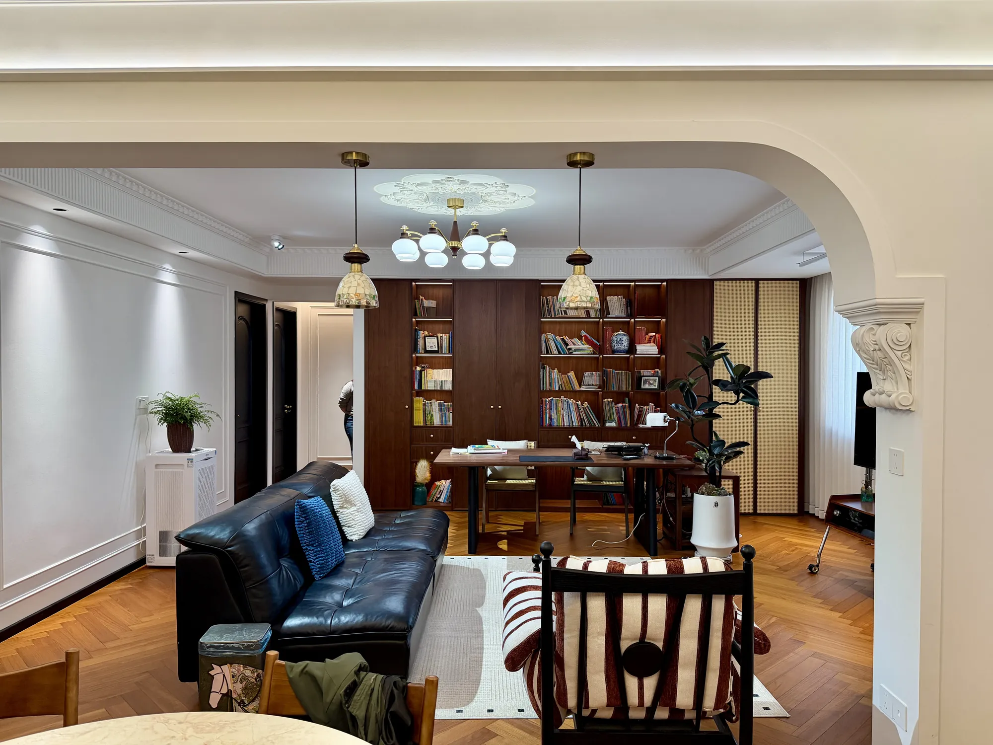 Closer living room view with black leather seating and walnut bookcase