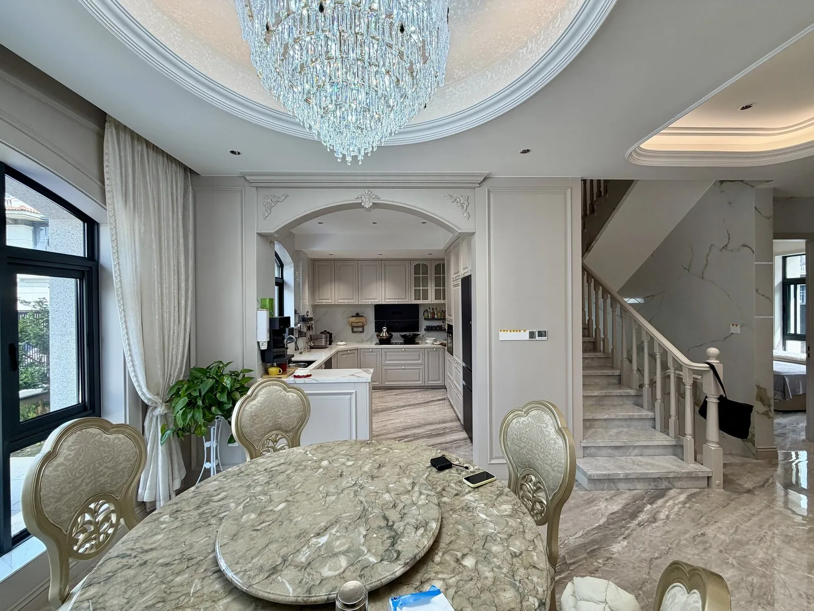 Dining room with round marble table, arched opening and chandelier
