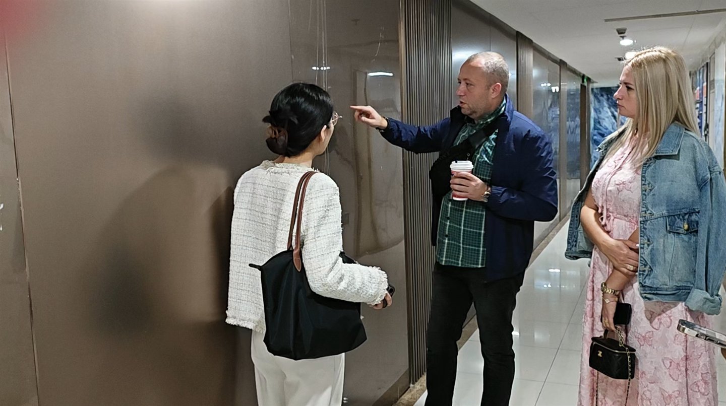 Client inspecting a wall surface with a Greenway representative in the showroom